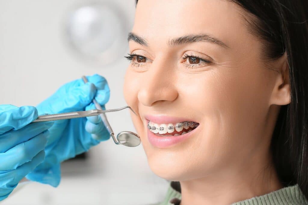 Dentist examining patient's teeth with mirror during dental checkup in clinical setting.